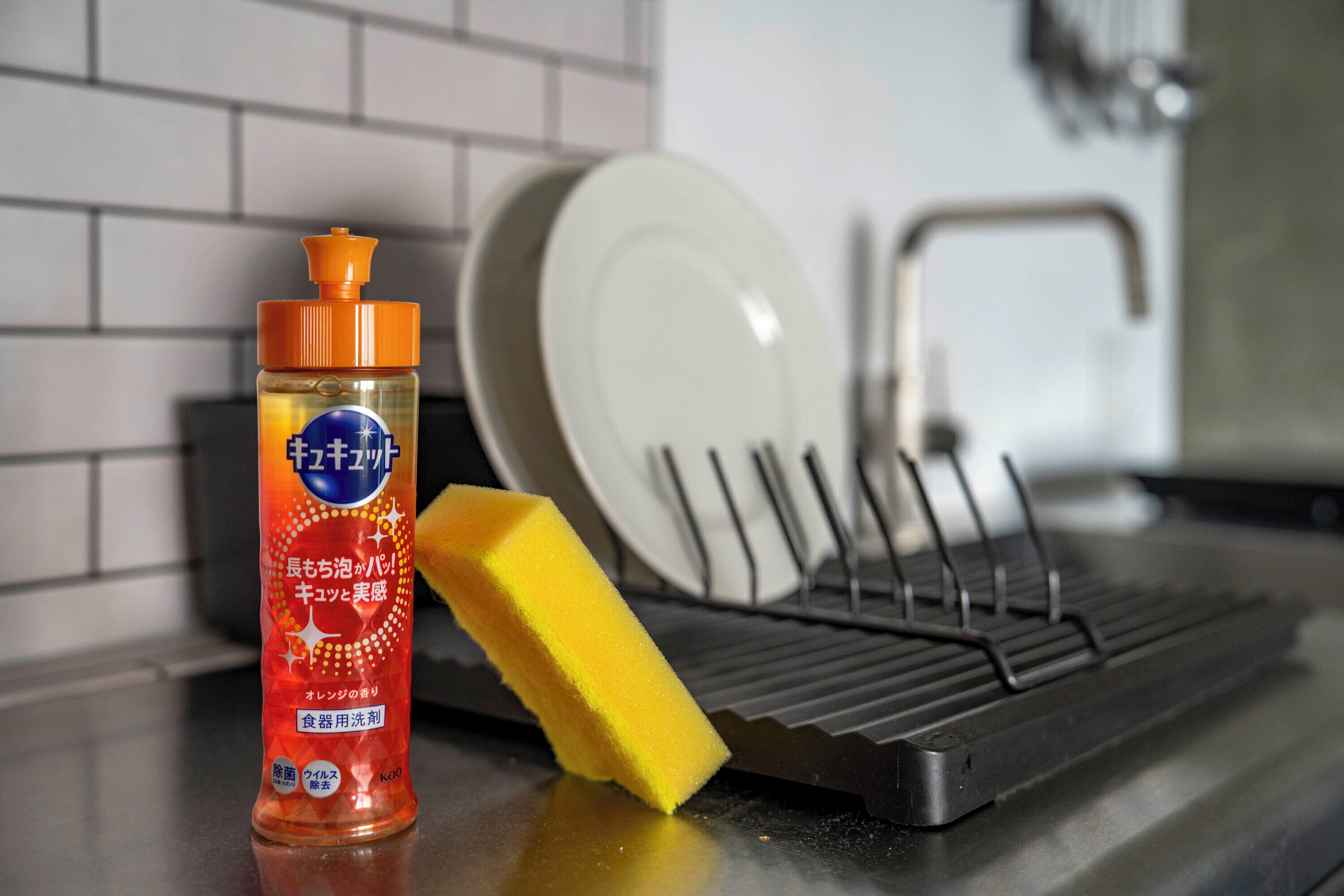 Une cuisine avec un égouttoir, une bouteille de liquide vaisselle et une éponge jaune.
