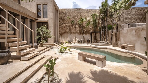 A modern outdoor pool area with a thatched roof, concrete steps, and minimalist furniture. - Villa Nubia at Bocoa Villas (Canggu)