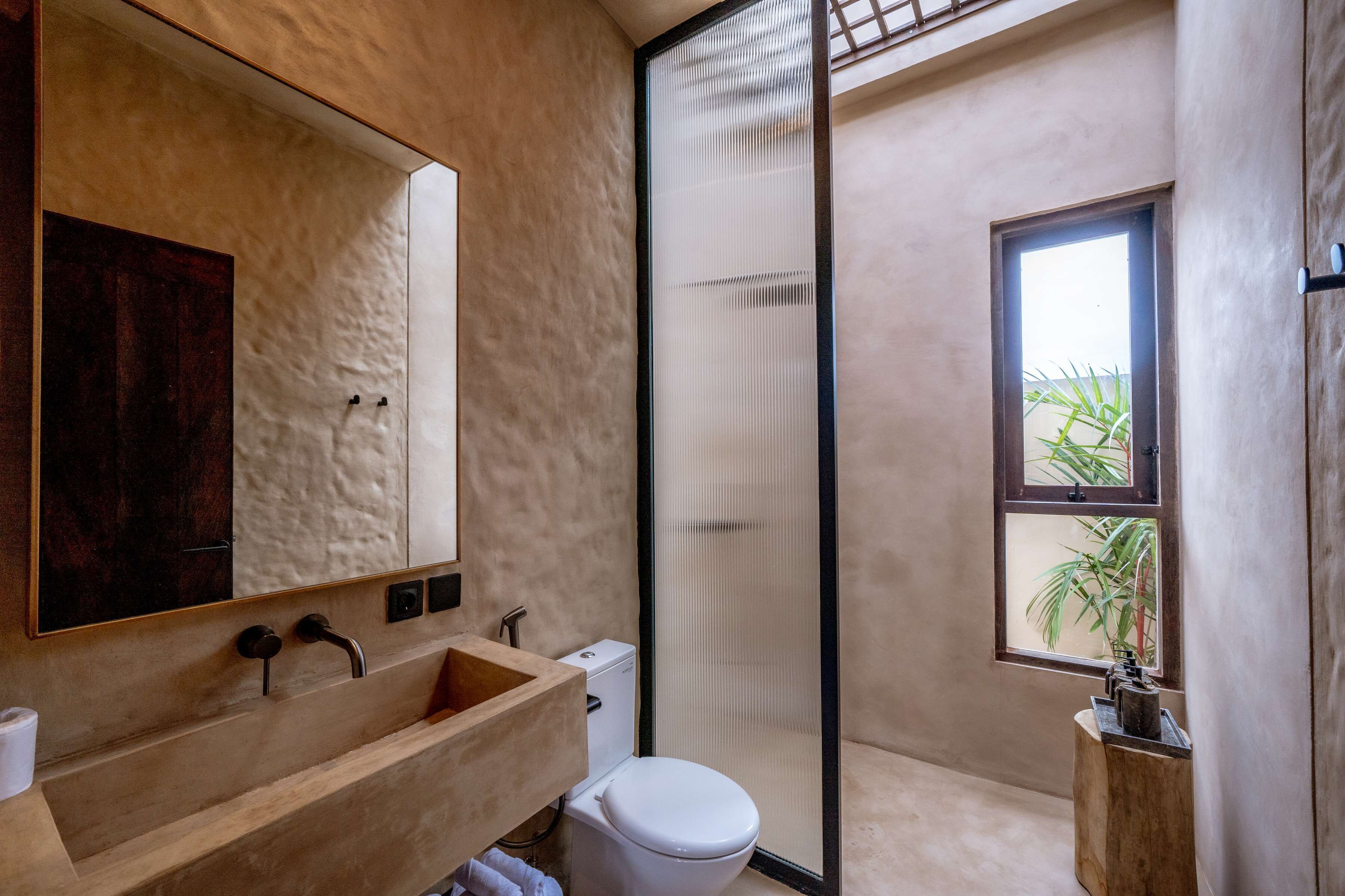A modern bathroom with a wooden vanity, a large mirror, a toilet, and a glass shower enclosure.