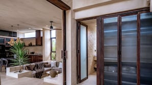 A spacious living area with a sofa, a coffee table, and a plant. There is a sliding glass door leading to a balcony. - Villa Nubia at Bocoa Villas (Canggu)