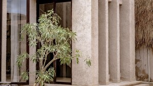 A modern building with a concrete facade, large windows, and a thatched wall. - Villa Nubia at Bocoa Villas (Canggu)