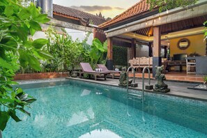 A swimming pool with lounge chairs and a covered seating area. - Villa Sampurna (Ubud)