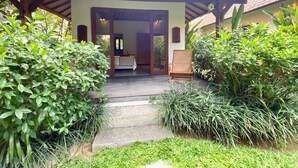 A covered entrance to a building with a tiled roof, a bench, and a chair outside. - Villa Kevin - 3BR Private Villa (Kecamatan Mengwi)