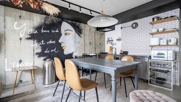 Una cocina moderna con comedor, que presenta una mesa grande, sillas y un mural en la pared.