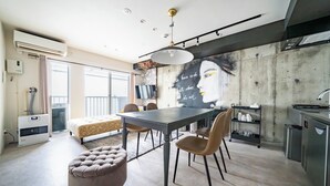 A modern kitchen with a dining area, featuring a large table, chairs, and a mural on the wall. - TAKETO STAY KOTONI 301 (Sapporo)