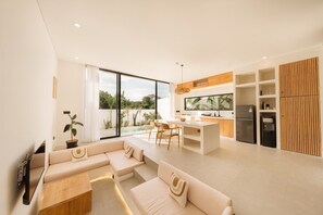 A modern kitchen with a dining area, a built-in refrigerator, and a large window overlooking a pool. - Alcove Boutique Villa C 1BR (Kecamatan Kuta Selatan)