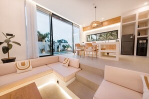Una sala de estar moderna con sofá, comedor y cocina.