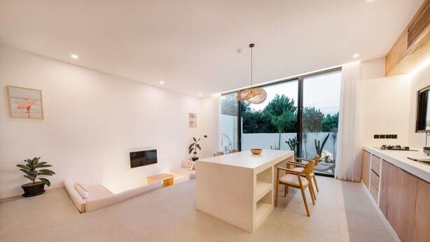Un interior moderno con comedor, televisor en la pared y un ventanal con vistas a zonas verdes.