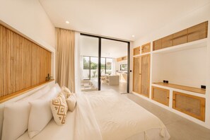 Un dormitorio moderno con una cama grande, un ventanal corredero que da a un balcón y un mueble empotrado para la televisión.