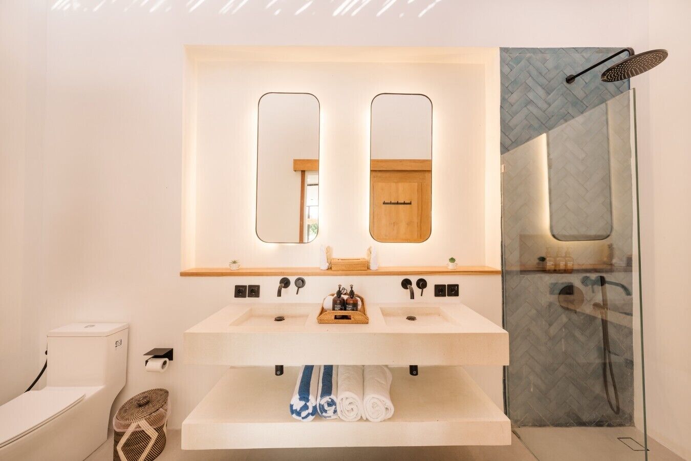 A modern bathroom with a double sink, two mirrors, a wooden vanity, and a glass shower enclosure.