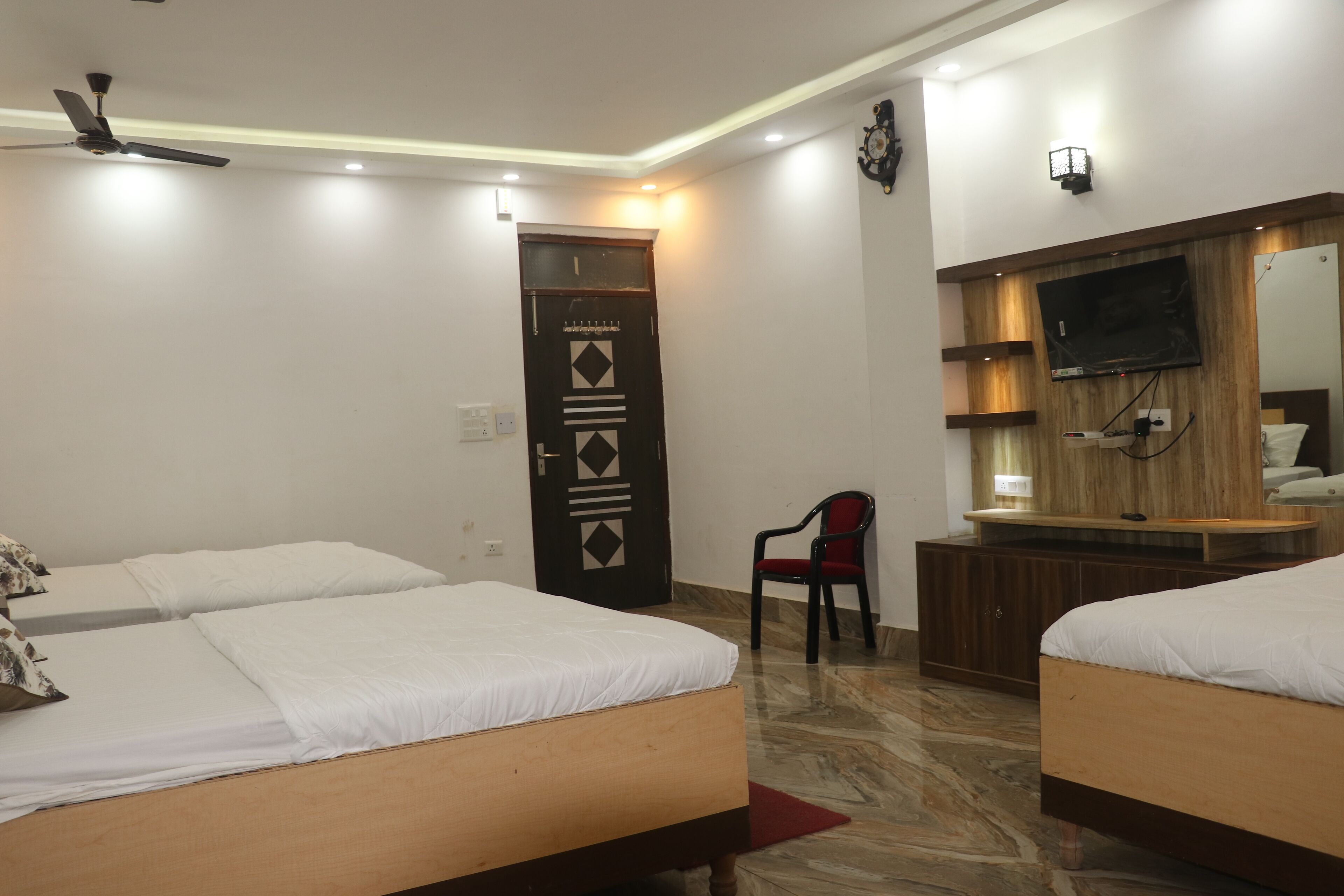 A hotel room with two beds, a TV, a desk, and a chair.