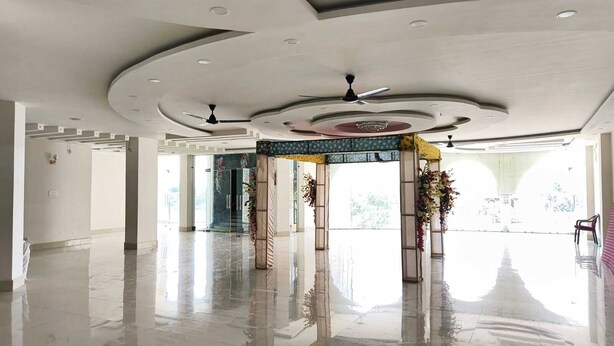 A spacious lobby with a polished floor, a central decorative arch, and ceiling fans. - Narayan Marriage Hall And resort  (Sitamarhi)