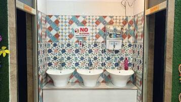 A restroom with three sinks, a 'NO ALCOHOL' sign, and a patterned tile wall.
