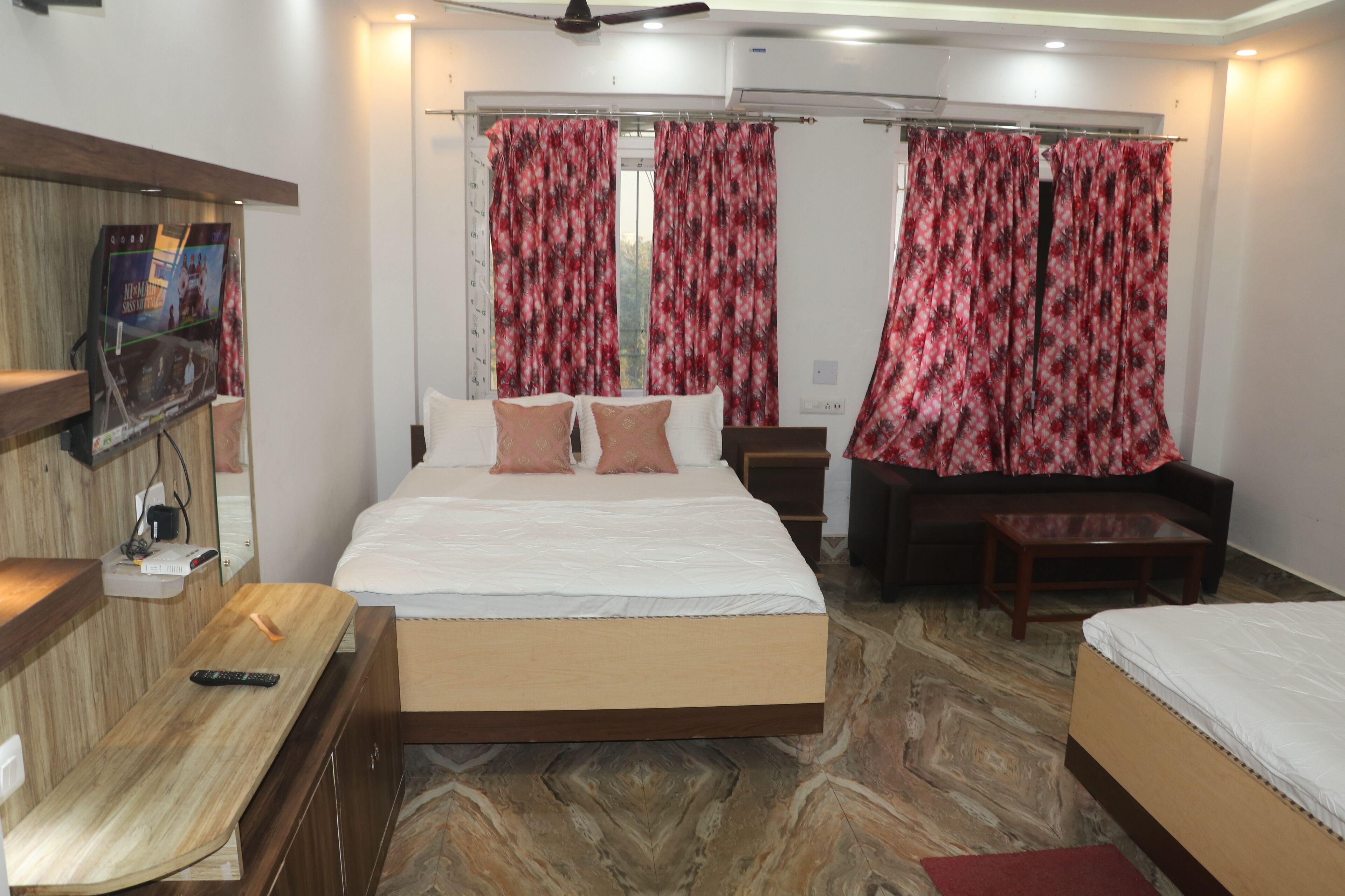 A hotel room with a bed, a sofa, a TV, and a desk.
