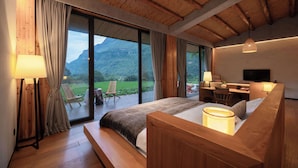 Makuuhuone, jossa on suuri ikkuna, puinen katto ja työpöytä tuolilla.