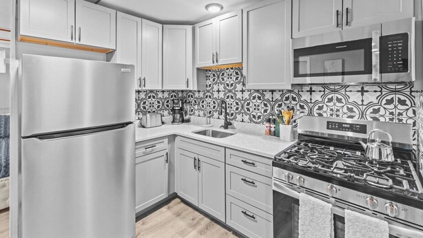 Una cocina moderna con electrodomésticos de acero inoxidable, armarios blancos y un salpicadero con diseño.