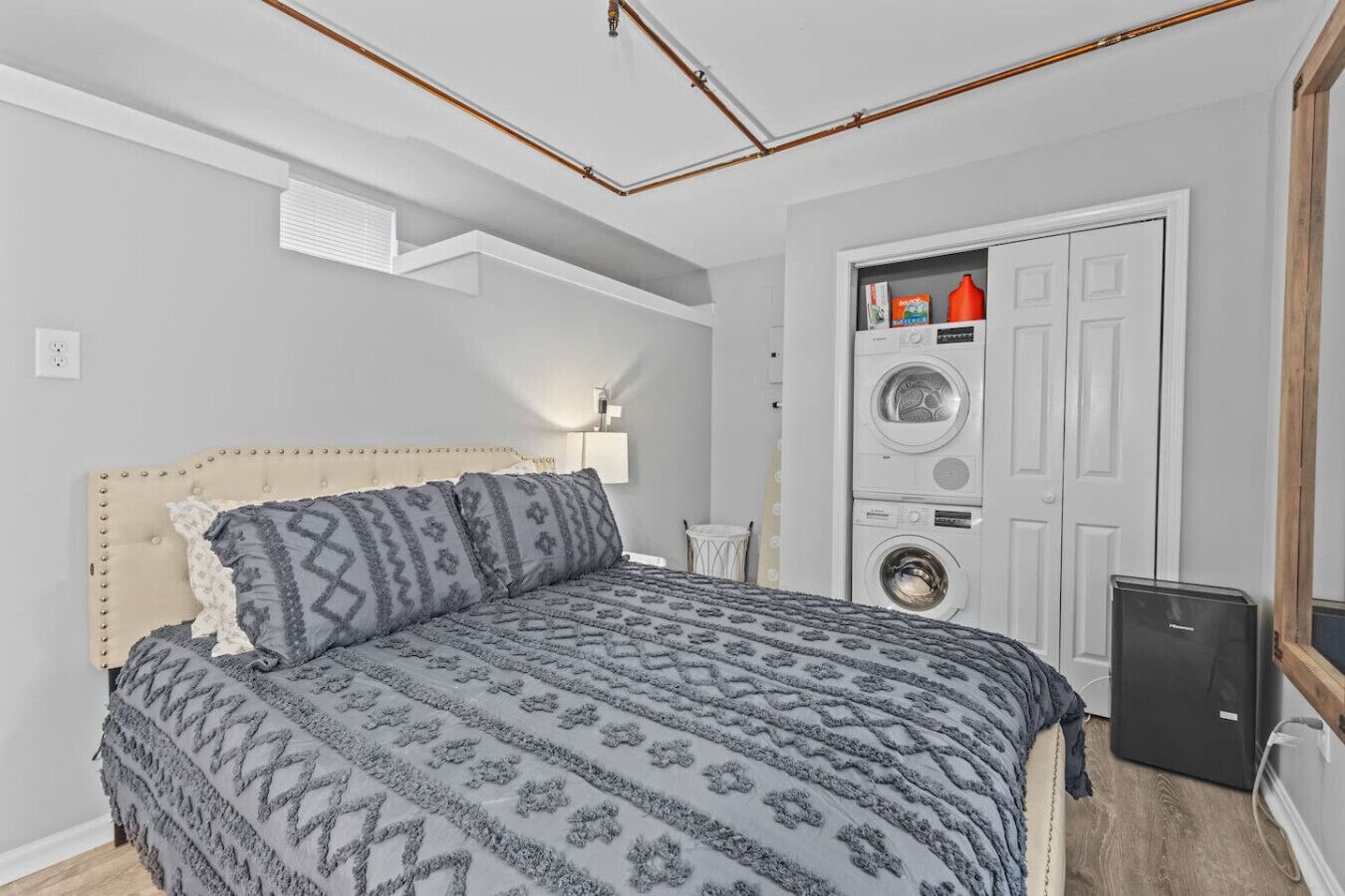 A bedroom with a bed, a washing machine, and a small cabinet.