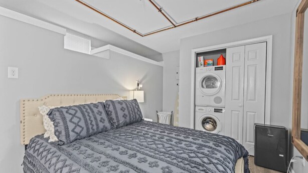 Ett sovrum med en säng, en tvättmaskin och ett litet skåp.