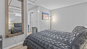 Un dormitorio con una cama grande, un espejo, un cuadro y una lámpara de pie.