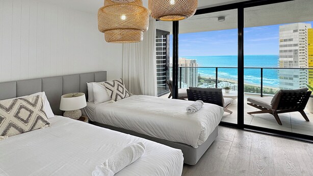 A hotel room with two beds, a balcony with a view of the ocean and buildings, and wicker lamps. - Luxury Oracle Tower 2 Ocean Views 2BR Lvl33 (Broadbeach)