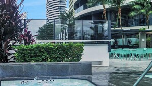 A modern hotel with a rooftop pool, surrounded by lush greenery and palm trees. - Luxury Oracle Tower 2 Ocean Views 2BR Lvl33 (Broadbeach)