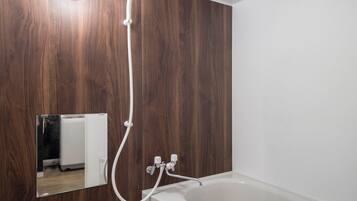 A bathroom with a wooden wall, a white bathtub, and a mirror reflecting a refrigerator.
