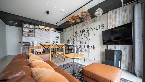 Un salon moderne comprenant un grand canapé, un coin repas et une cuisine.
