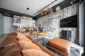 Ein modernes Wohnzimmer mit einem großen Sofa, einem Essbereich und einer Küche.