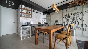 Une cuisine moderne avec des carreaux de céramique blancs disposés en motif métro, des étagères en bois et un coin repas comprenant une table et des chaises en bois.