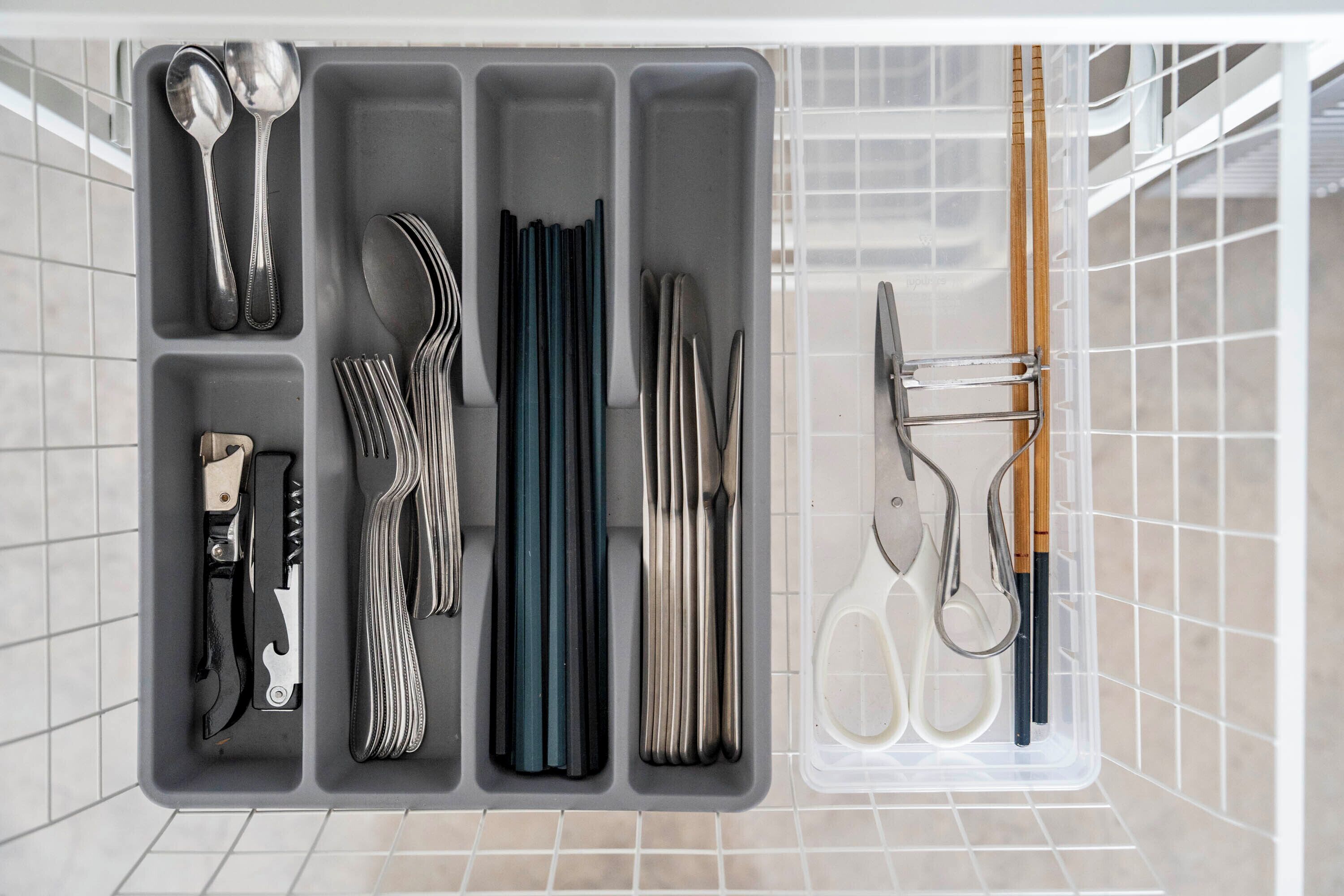 A kitchen drawer with utensils organized in compartments.