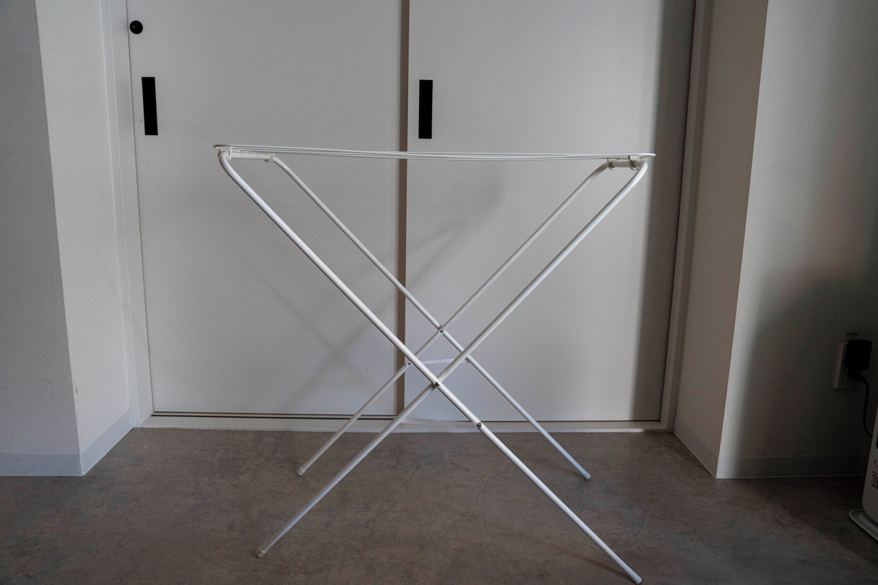 A white metal drying rack in a room with beige carpet and white walls.