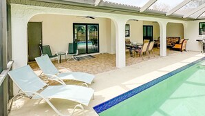 A covered outdoor swimming pool area with lounge chairs, a table, and a patio with chairs. - 5-bedroom home in Port Charlotte (Port Charlotte)