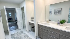 A modern bathroom with a skylight, a large vanity, and a walk-in shower. - 5-bedroom home in Port Charlotte (Port Charlotte)