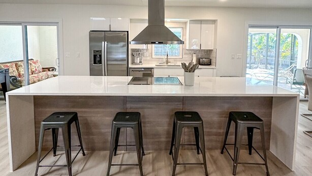 A modern kitchen with a central island, stainless steel appliances, and a large window providing natural light. - 5-bedroom home in Port Charlotte (Port Charlotte)