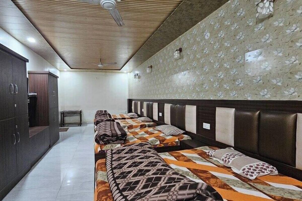 A hotel room with a long bed, a wardrobe, and a ceiling fan.