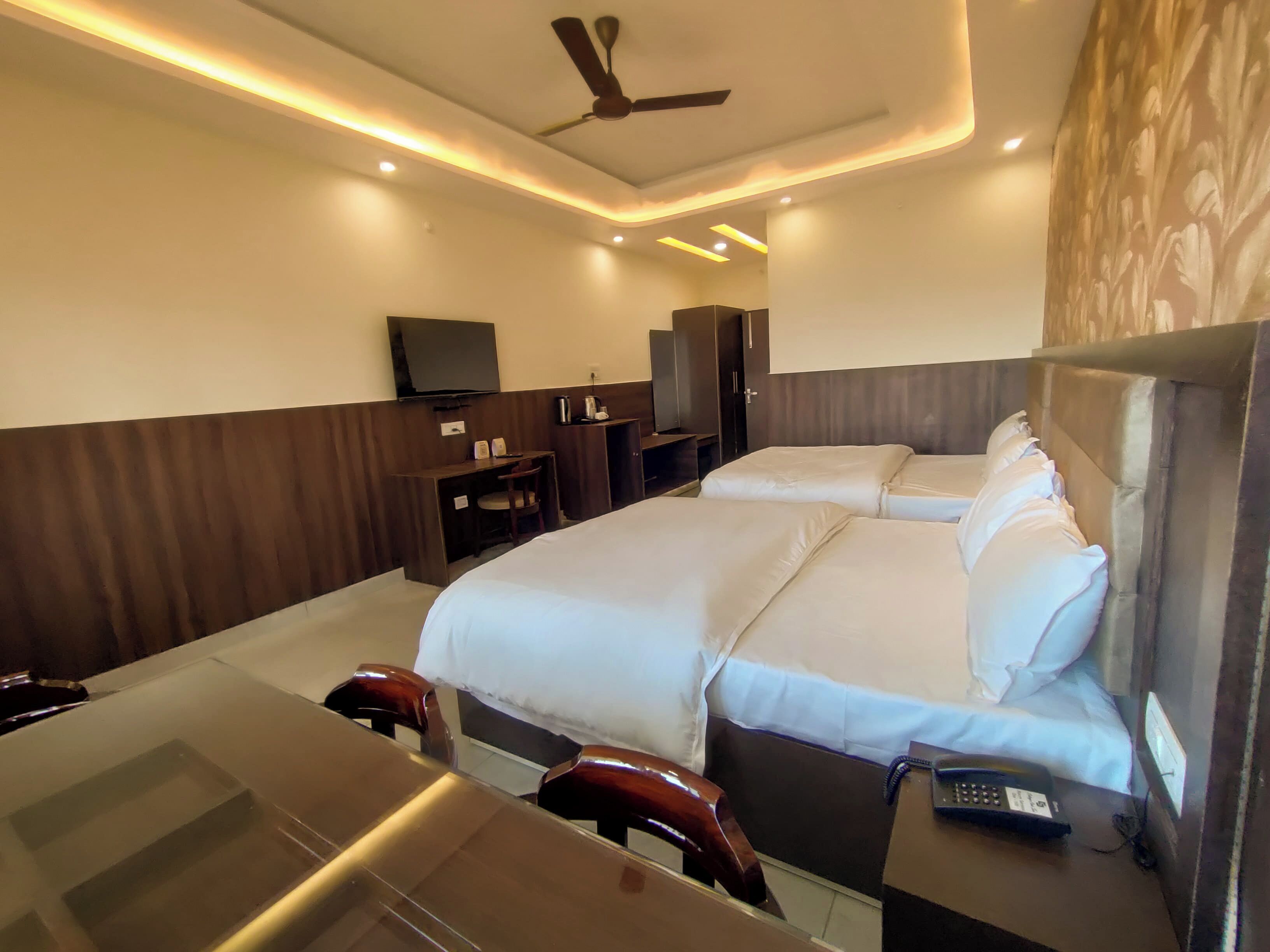 A hotel room with a bed, desk, chair, and a ceiling fan.
