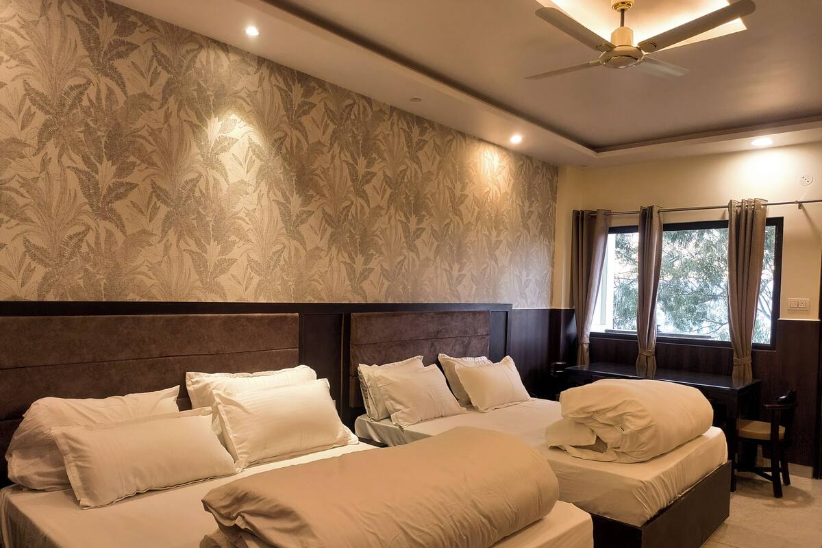 A hotel room with two beds, a ceiling fan, and a window with curtains.
