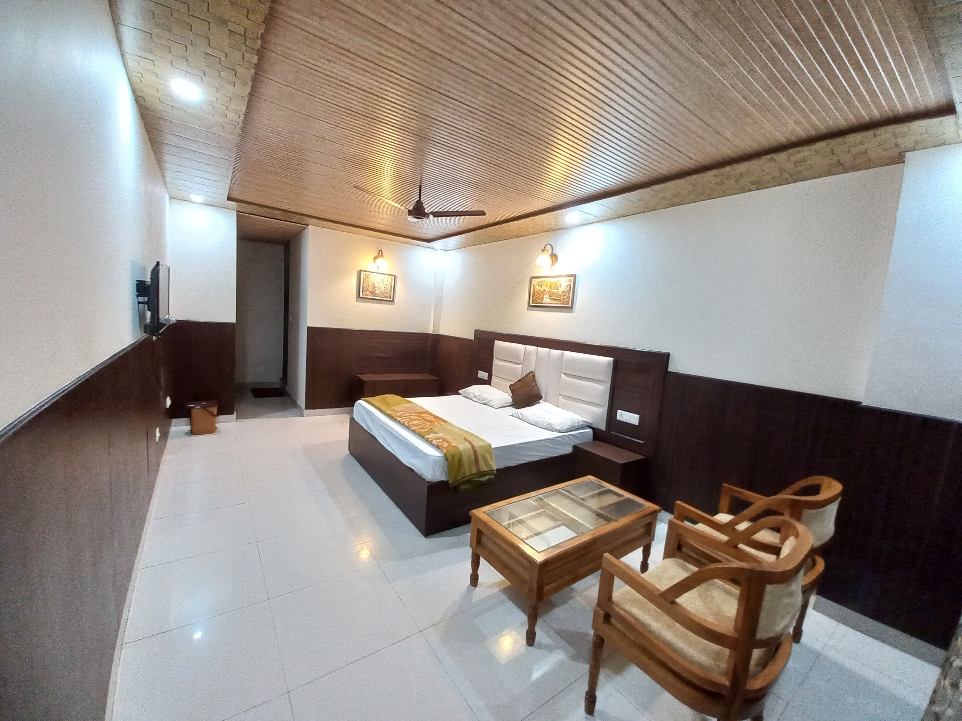 Una habitación de hotel con cama, mesitas de noche, una silla y una pequeña mesa.