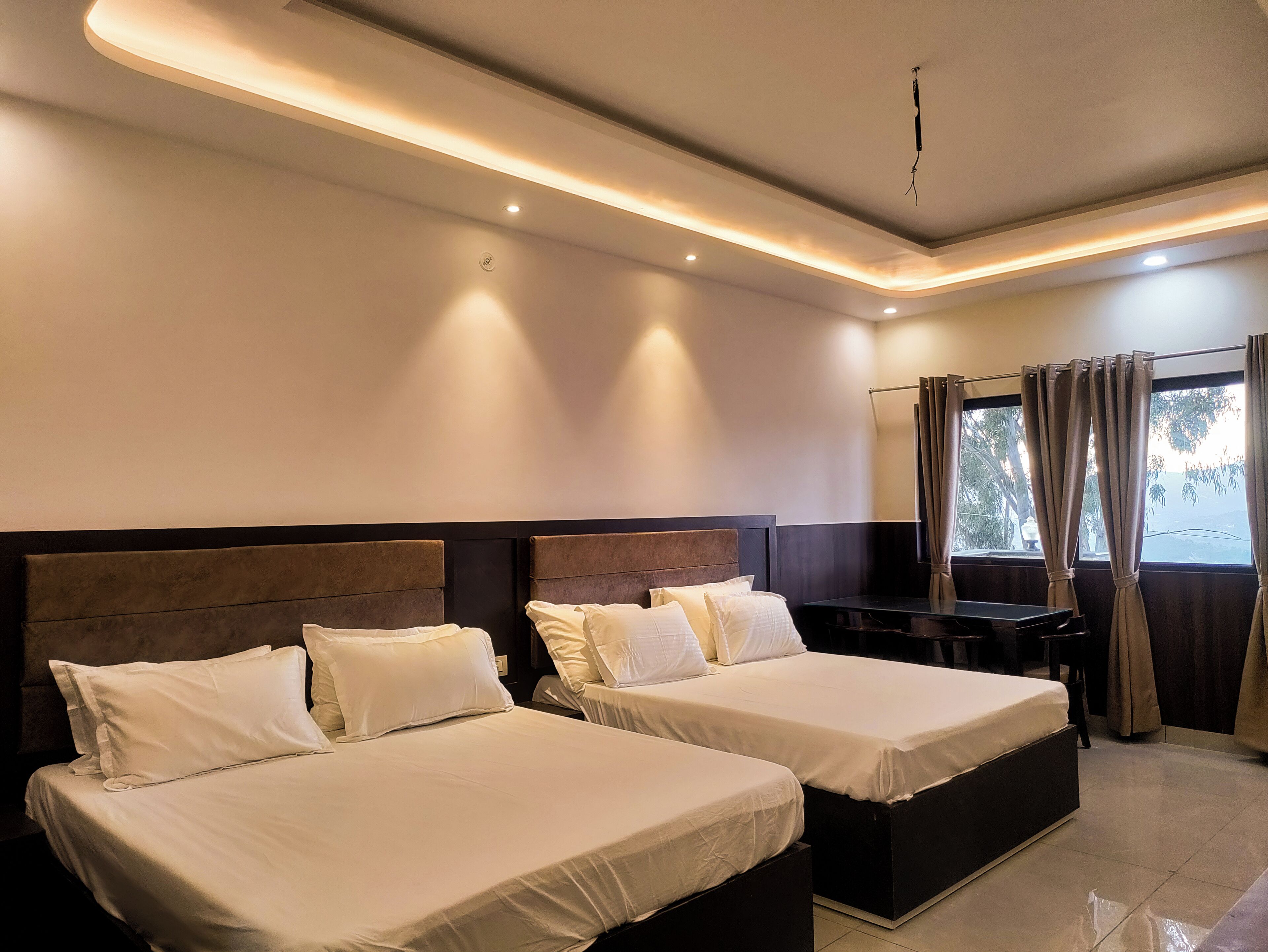 A hotel room with two beds, a desk, and a window with curtains.
