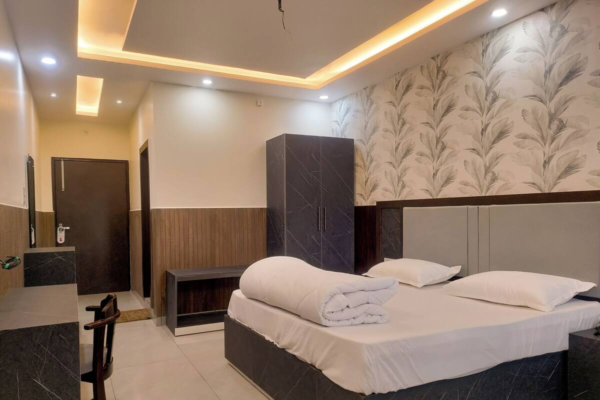 A modern hotel room with a large bed, a wardrobe, a desk, and a bathroom.