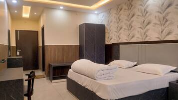 Una habitación de hotel moderna con una cama grande, un armario, un escritorio y un baño.