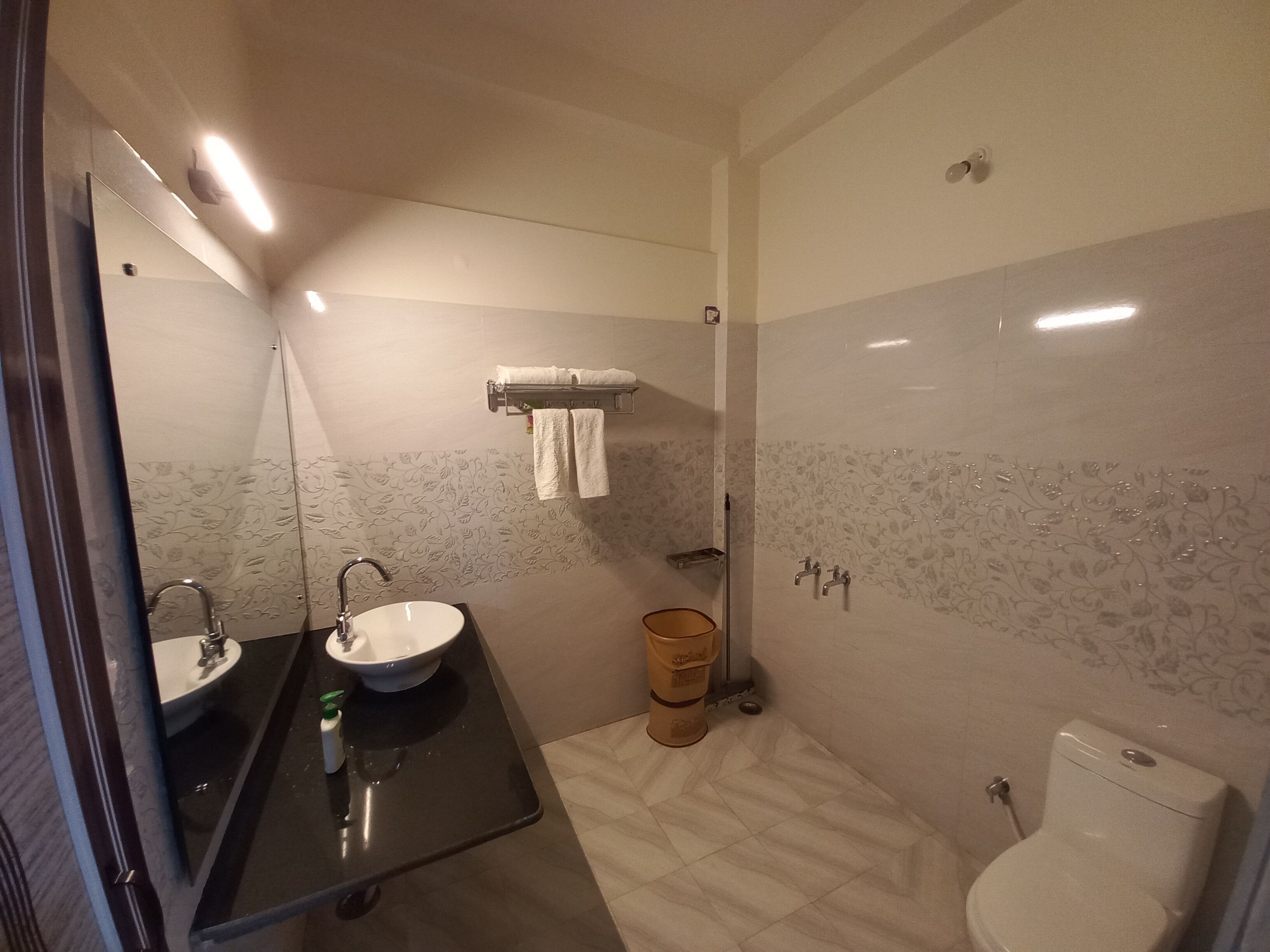 Casa de banho com lavatório, espelho, porta-toalhas, sanita e zona de duche.