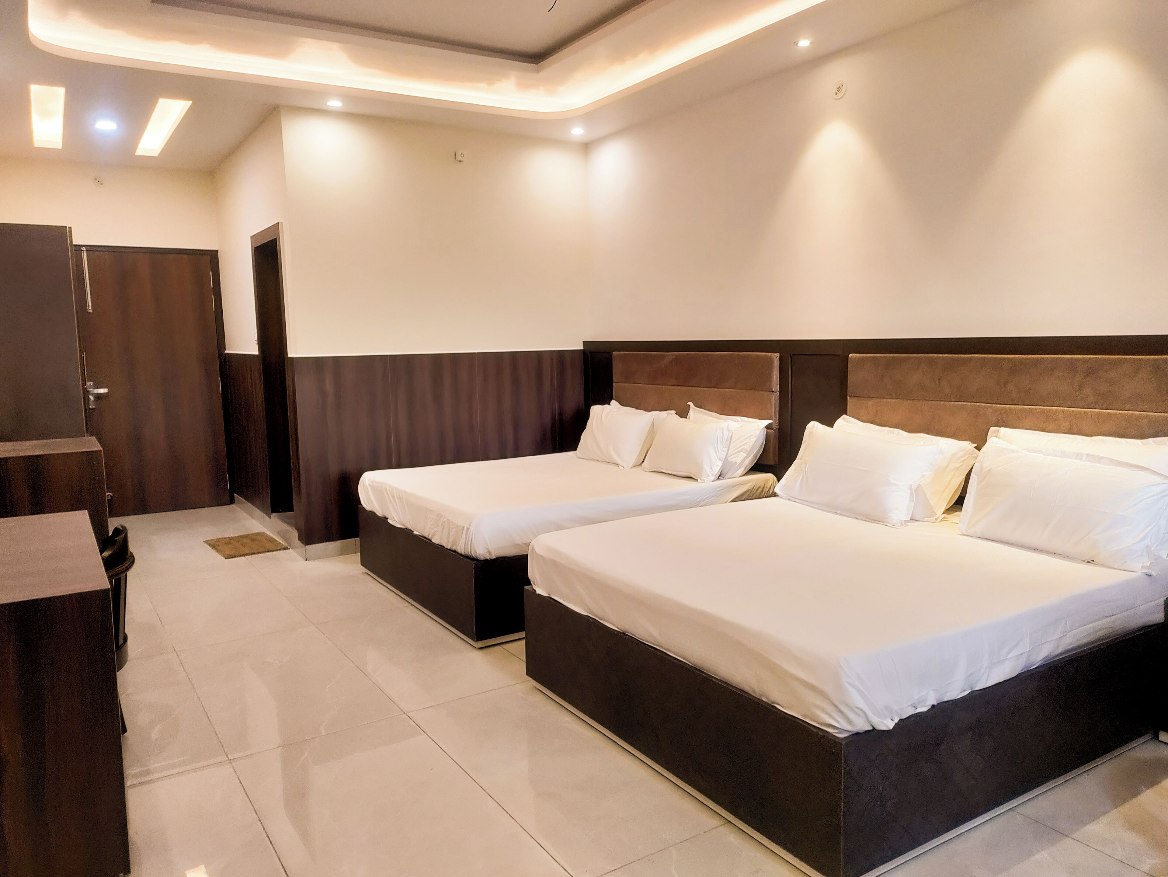 A hotel room with two beds, a desk, and a wardrobe.