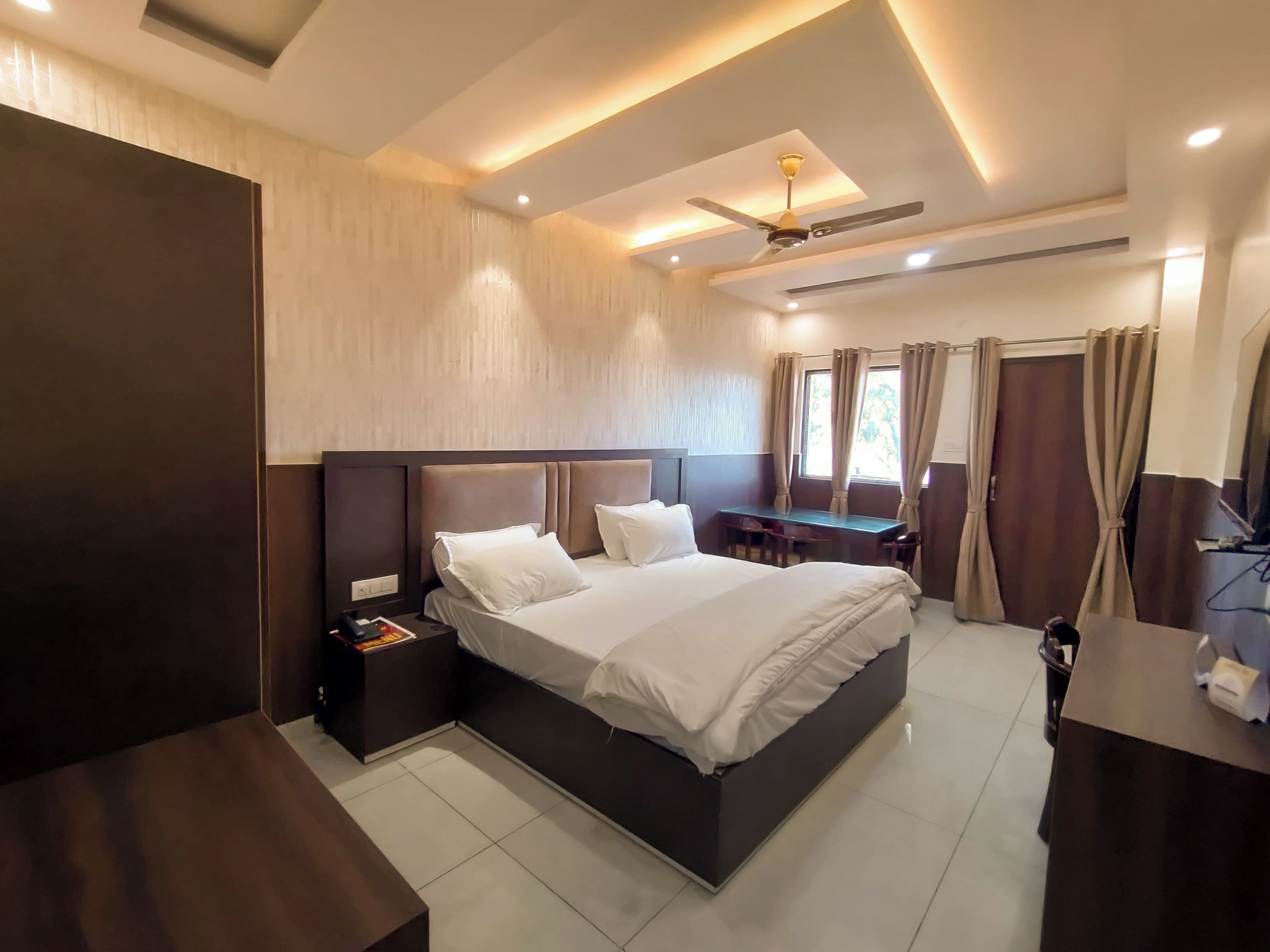 Ein modernes Hotelzimmer mit einem großen Bett, einem Schreibtisch und einem Deckenventilator.