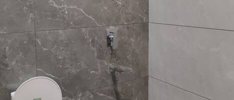 Ein Badezimmer mit Toilette, Bidet und Duschkopf.