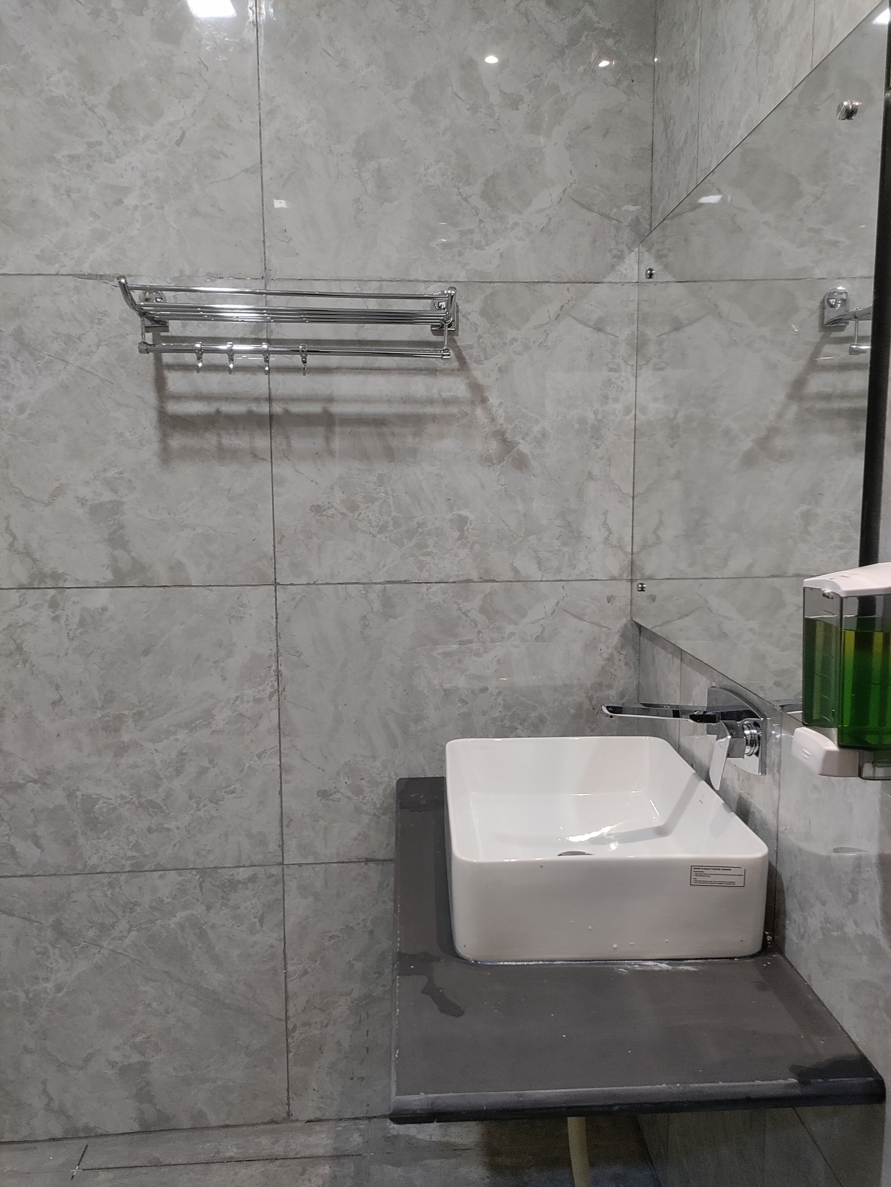 A bathroom with a white sink, a chrome towel rack, and a mirror.