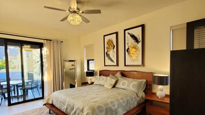 A spacious bedroom with a large bed, a ceiling fan, and a view of the outdoors through a sliding glass door. - Pristine 3-bed, 3.5-bath villa with mountain, golf course, sea views & hot tub 
 (Loreto)