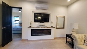 A living room with a fireplace, television, and a mirror. - Pristine 3-bed, 3.5-bath villa with mountain, golf course, sea views & hot tub 
 (Loreto)