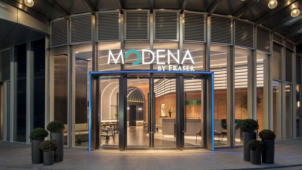 A modern hotel entrance with glass doors, a neon sign, and potted plants. - Modena By Freser Shenzhen (Shenzhen)