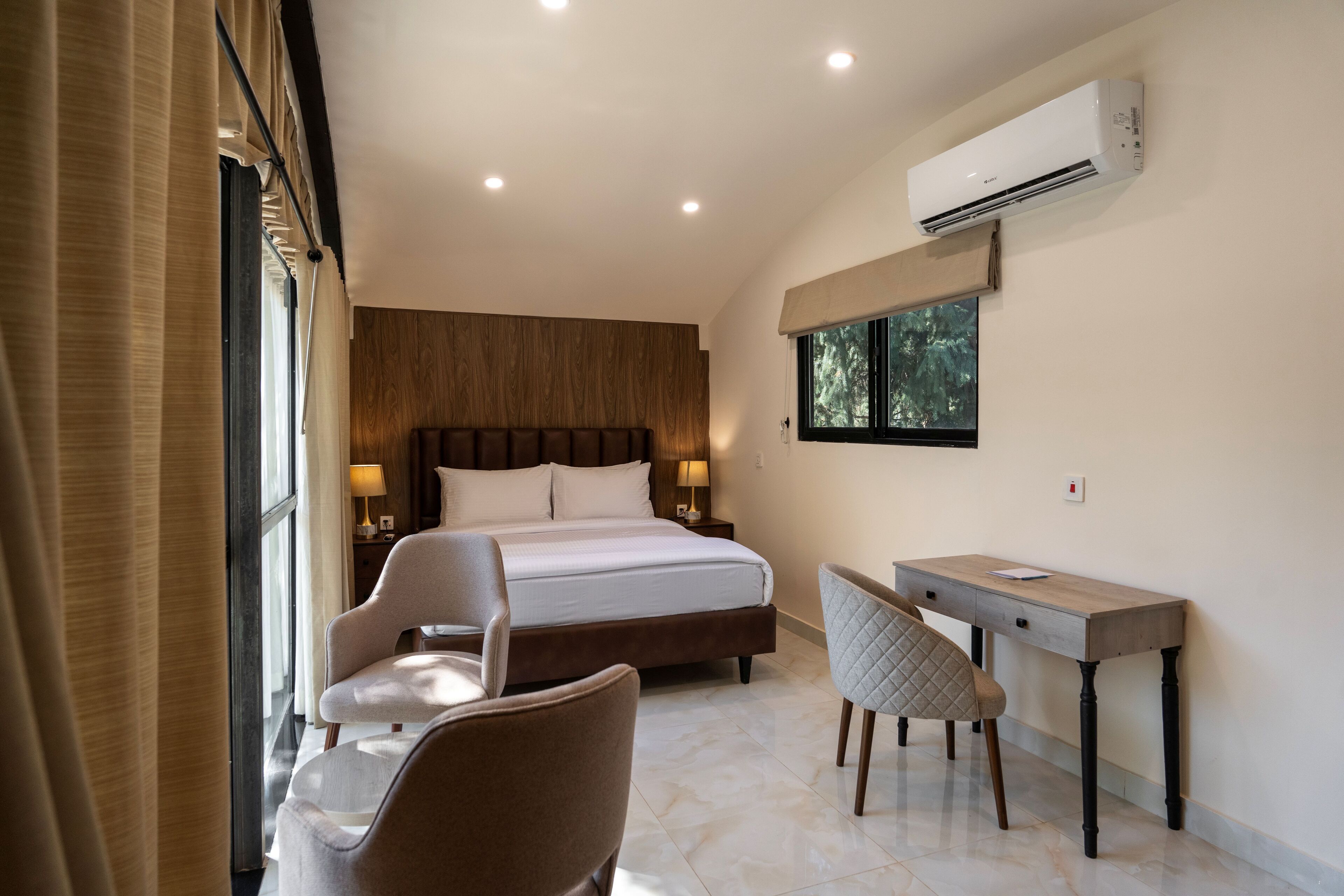 Une chambre à coucher comprenant un lit, des tables de chevet, un bureau et un appareil de climatisation.